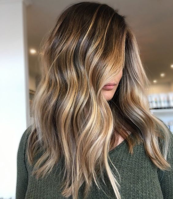 long dark brunette hair with golde blonde balayage and beach waves is a very chic and stylish idea to rock