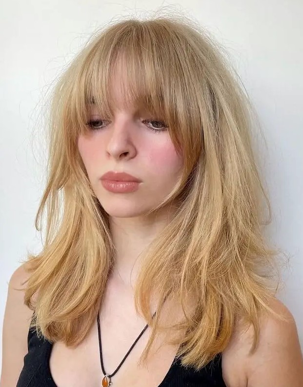 Long golden blonde hair with layers and long and expended Bardot bangs is a truly Bardot inspired hairdo