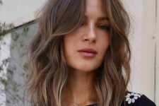 messy brown medium-length hair with central part, slight blonde highlights, waves and face-framing layers