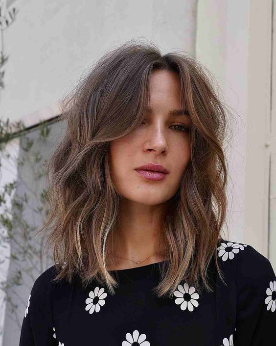 Messy brown medium length hair with central part, slight blonde highlights, waves and face framing layers
