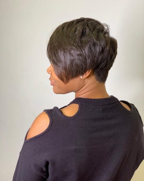 a black long pixie with long side bangs, a lot of layers and the hairline at the back that tapers into a V-shape