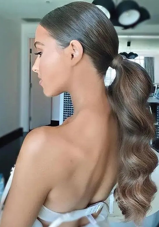 a beautiful and elegant wavy low ponytail with a sleek and shiny top is a stylsih idea for a glam girl