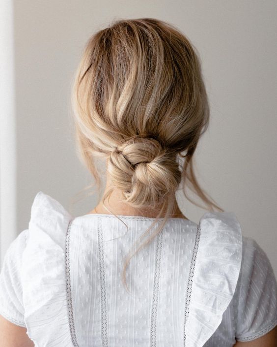 a beautiful messy and wrapped low bun with a wavy textural top and face-framing locks down