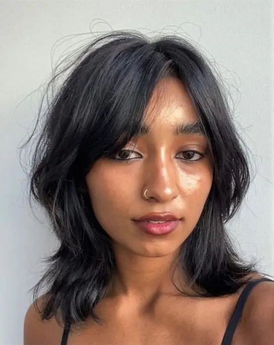 a black outgrown bob with central parting and curtain bangs plus waves and texture is amazing