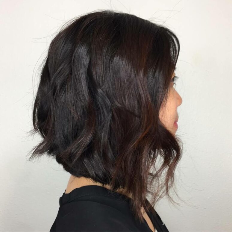a black razor cut lob with an angle and burgundy highlights is a flattering solution that looks super nice