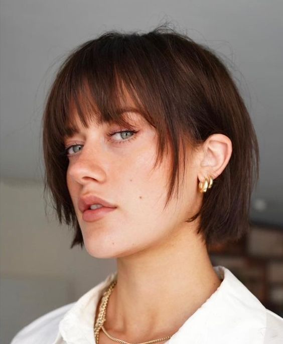 a blunt dark brunette bob with wispy bangs and face-framing layers is a catchy idea to try right now