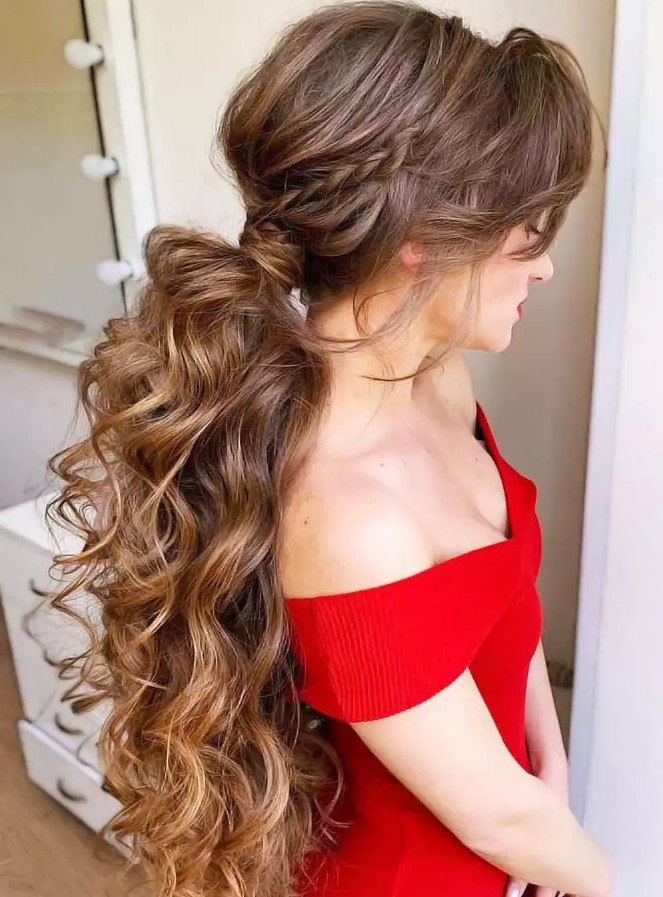 a braided and curled pony with long bangs, where every single lock stands out to form a totally voluminous silhouette while long bangs give a stunning face-framing effect