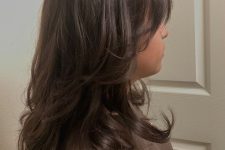 a brunette medium butterfly haircut with curled ends and a lot of volume is a chic and eye-catching idea