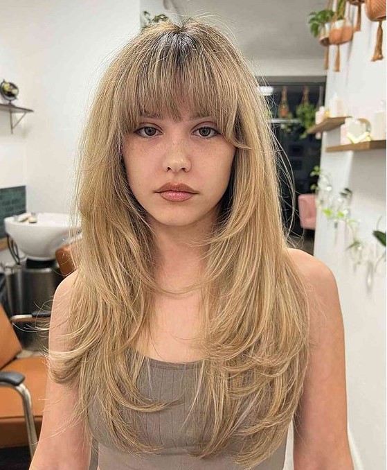 a buttefly haircut done on honey blonde hair with layered bangs and a lot of feathered layers is a chic and lovely idea