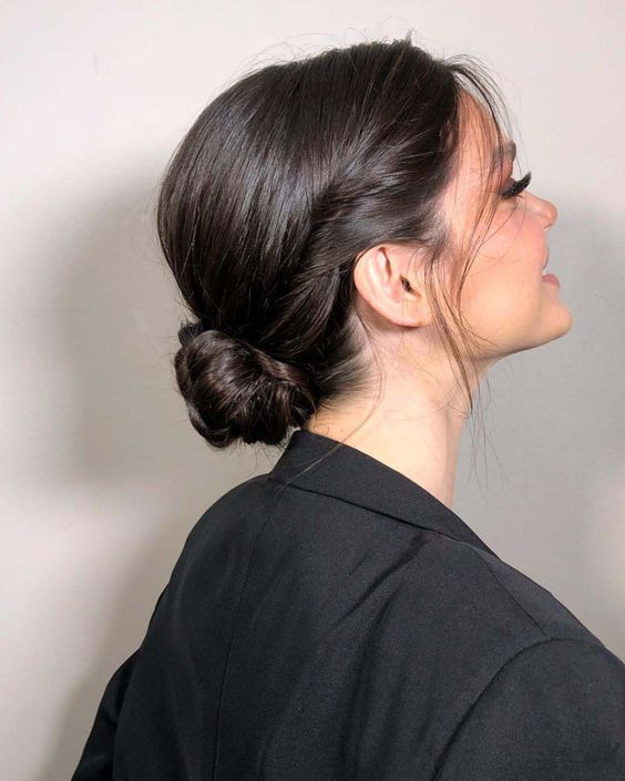 A chic low bun hairstyle with a bump, a tight twisted bun and some face framing locks is a cool idea