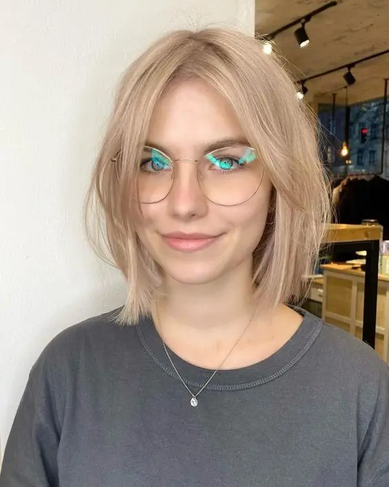 a colb blonde long bob with curtain bangs that add a bit of volume and interest to the hairstyle