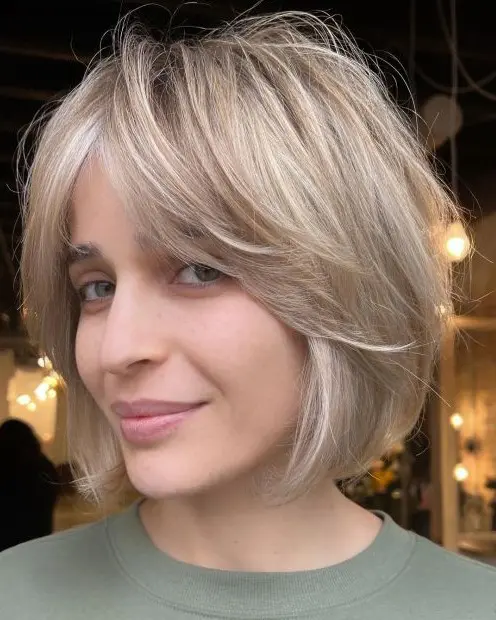 A cold blonde feathered chin length bob with curtain bangs is a very fresh and modern solution that brings movement