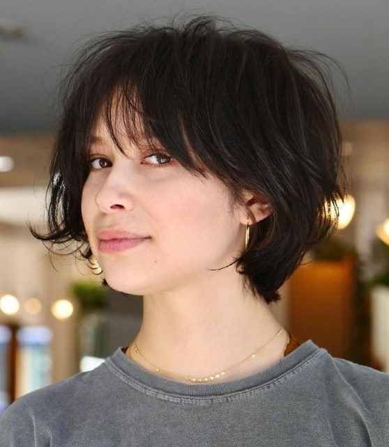 a cool dark brown feathered short bob with wispy bangs looks a bit messy but very chic and cool