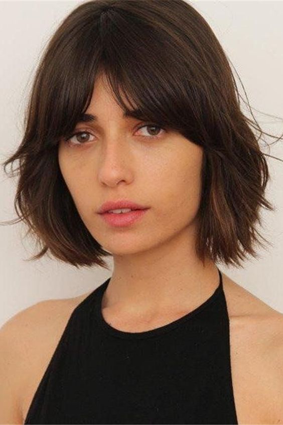 a dark brown bob with bottleneck bangs and textured shaggy hair is a cool 70s inspired idea