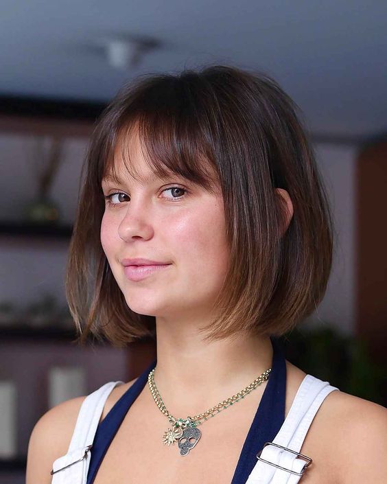 a dark brown chin-length bob with a slight ombre effect and wispy bangs is a cool idea to try