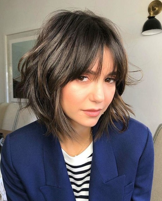 a dark brown chin-length shaggy bob with wispy bangs is a relaxed and lovely idea for an effortlessly chic look