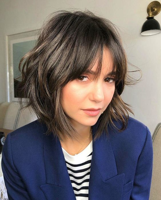 a dark brown chin-length shaggy bob with wispy bangs is a relaxed and lovely idea for an effortlessly chic look