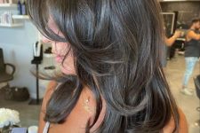a dark brunette butterfly haircut with curled ends and a bit of volume is a chic and eye-catching idea