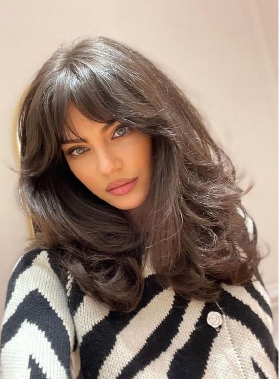 a dark brunette medium butterfly haircut on thick hair, with bottlneck bangs and waves is wow