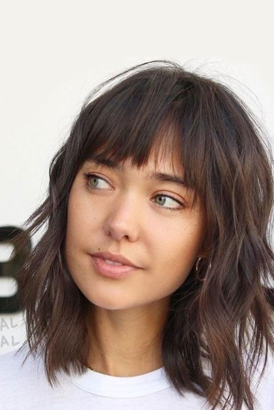 A dark brunette wavy medium length hairstyle with shaggy layers and wispy bangs is a lovely and relaxed idea to try for summer