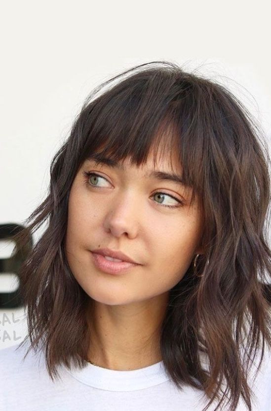 a dark brunette wavy medium-length hairstyle with shaggy layers and wispy bangs is a lovely and relaxed idea to try for summer