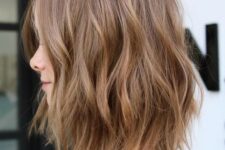 a delicate and soft brown choppy long bob with subtle highlights and waves and face-framing layers is cool
