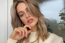 a delicate mushroom blonde shade, medium wavy hair and long curtain banfs for a stylish and relaxed look