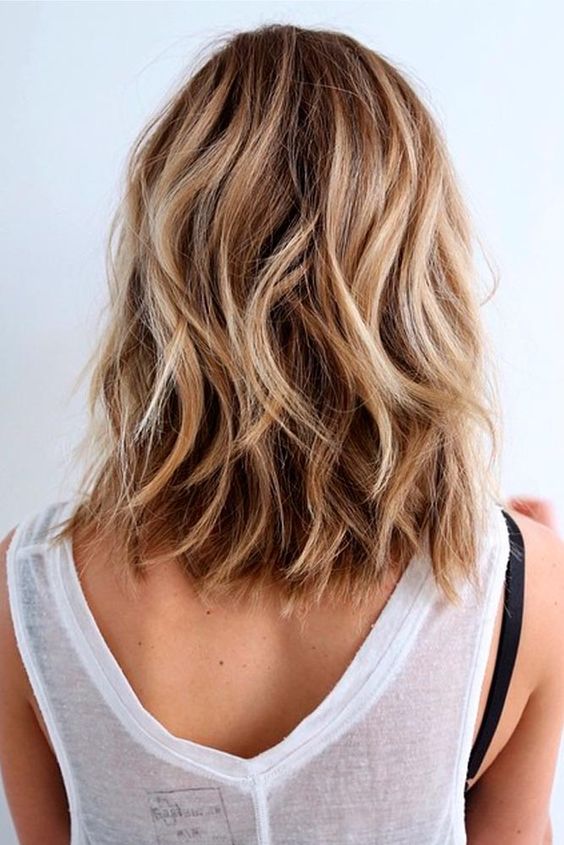 A dreamy beach hairstyle with medium length brone hair, blonde hihglights and waves is perfect for summer