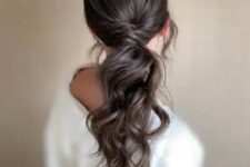 a dreamy wavy low ponytail with twisted hair and a sleek top plus locks framing the face is a lovely idea for a romantic touch
