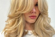 a fab blonde medium-length butterfly haircut with curtain bangs and curled ends is a cool idea
