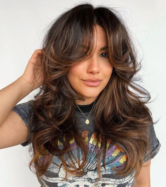 a fantastic dark brunette butterfly haircut with caramel balayage, side bangs and waves all over is a gorgeous idea