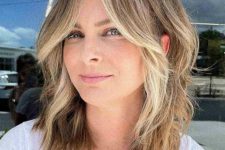 a flattering face-framing wavy lob with curtain bangs and blonde highlights and money piece is a fresh and cool idea