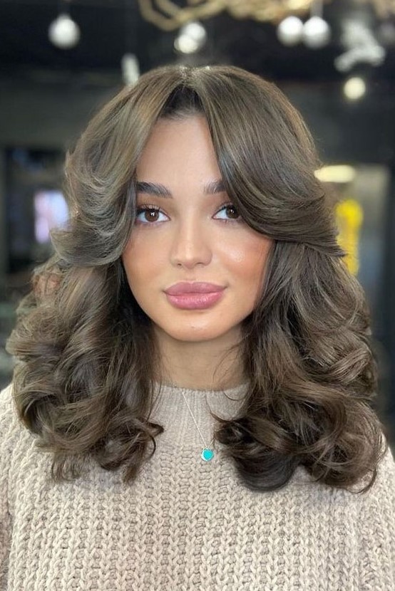 a gorgeous brunette medium butterfly haircut with side bangs and curls is a fantastic and super glam idea to try