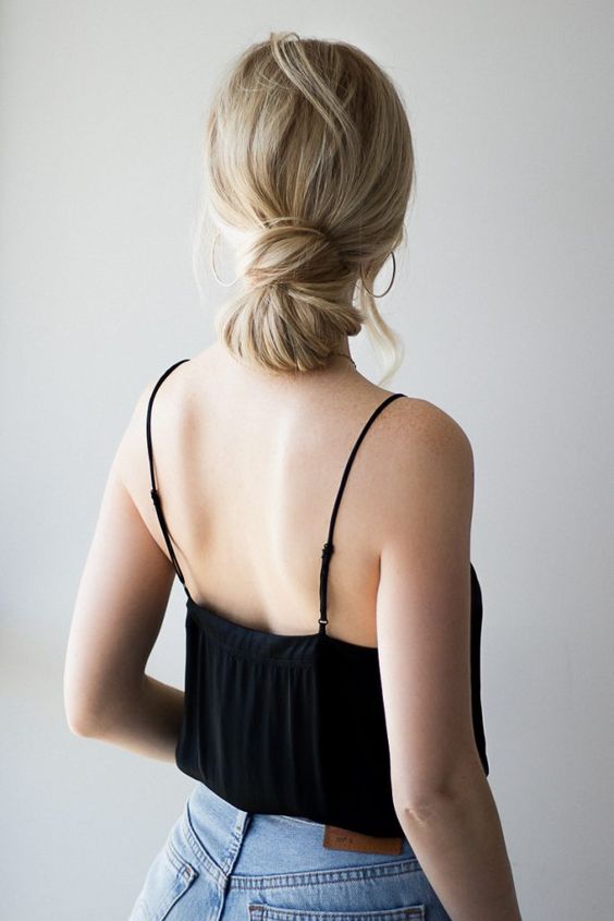 a knotted low bun with a messy and wavy top is a cool idea for long hair