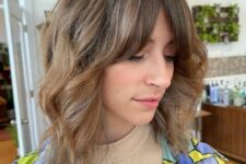 a light brown long wavy bob with curtain fringe and highlights is a cool hairstyle with minimum effort