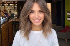 a light brunette shoulder-length hairstyle with curtain bangs and messy texture looks shaggy and cool