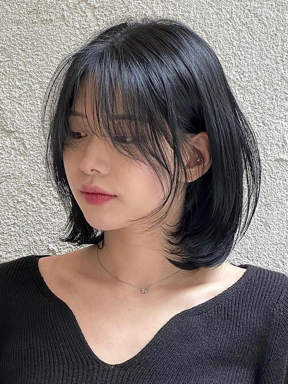 a long black bob with curved ends and long wispy bangs that beautifully frame the face is pure chic