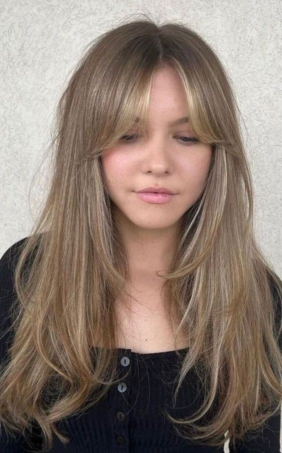 a long bronde butterfly haircut with blonde highlights and curtain bangs is a lovely idea inspired by the 70s