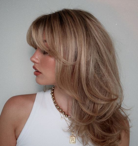 a lovely blonde butterfly haircut with highlights and side and bottleneck bangs is a gorgeous idea