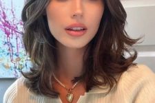 a lovely medium-length brunette butterfly haircut with wavy ends and middle part is a cool solution for trying now