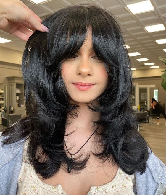 a medium black butterfly haircut with curtain bangs and curled ends and a shiny touch is amazing