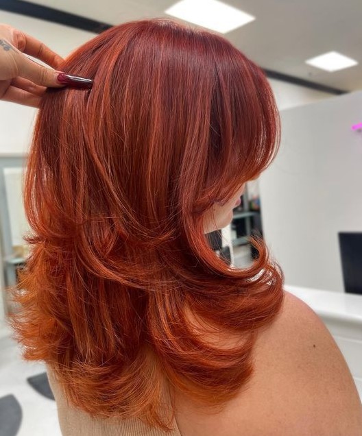 a medium butterfly haircut done in super bold red shades, with highlights and curled ends is amazing