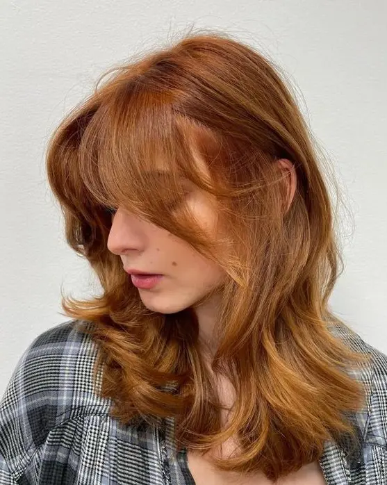 a medium butterfly haircut with some golden blonde highlights done in a super bold ginger color, it looks gorgeous