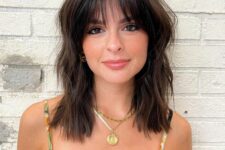 a medium length dark brown haircut with waves and wispy bangs is a cool idea that doesn’t require much maintenance