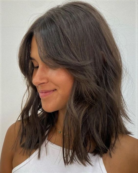 a medium-length shaggy dark brunette hairstyle with curtain bangs and a bit of volume is a cool idea