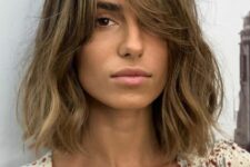 a messy bronde long bob with a darker root and waves plus curtain bangs to soft the look even more