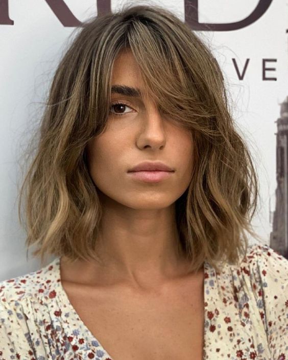 a messy bronde long bob with a darker root and waves plus curtain bangs to soft the look even more