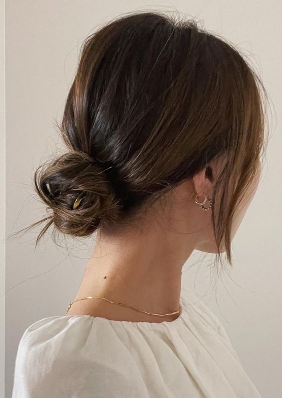 a messy low bun with a volume on top and some face-framing locks is a good idea for both medium and long hair