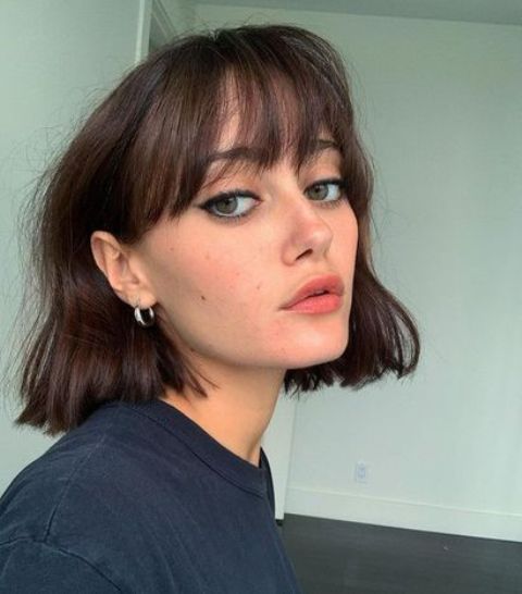 a messy wavy dark brown chin-length bob with wispy bangs is a stylish and relaxed idea, perfect for summer