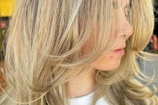 a pretty blonde medium-length butterfly haircut with a darker root and curled ends is a lovely solution to try